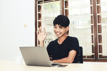 The man in the black Asian shirt was sitting in front of the laptop on a video call