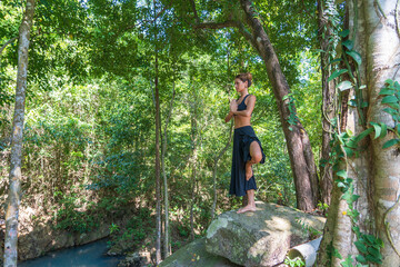 Naklejka na ściany i meble Young caucasian brunette girl is meditating in nature at tropical garden in summer, Thailand