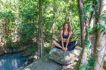 Young caucasian brunette girl is meditating in nature at tropical garden in summer, Thailand