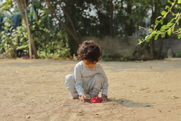 Close-up of An Indian child playing with a red hibiscus flower.