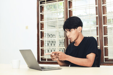 Fototapeta premium The Asian man was sitting pointing at the laptop