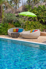 Obraz premium Swimming pool with relaxing beds and sun umbrella in tropical garden