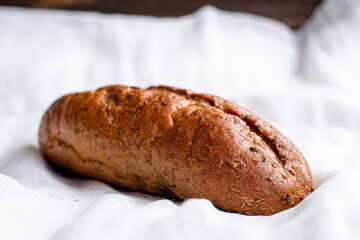 rye freshly baked bread roll on a white cloth napkin