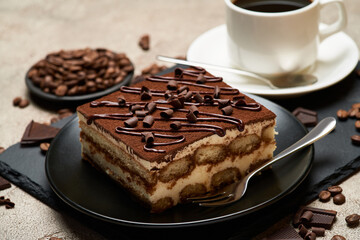Portion of Traditional Italian Tiramisu dessert and cup of coffee on grey concrete background
