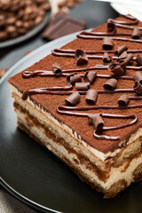 Portion of Traditional Italian Tiramisu dessert and cup of coffee on grey concrete background