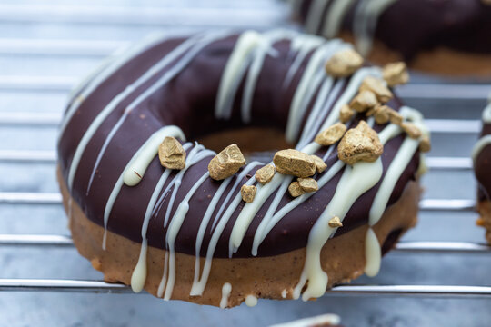 Closeup shot of an appetizing chocolate-covered raw donut with nuts sprinkles on lurry background