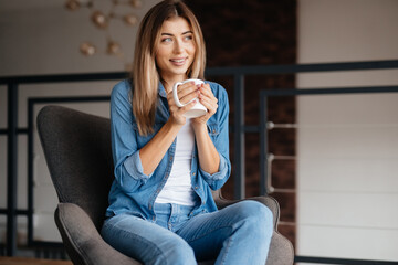 Inspired lady in blue shirt enjoying coffee at home