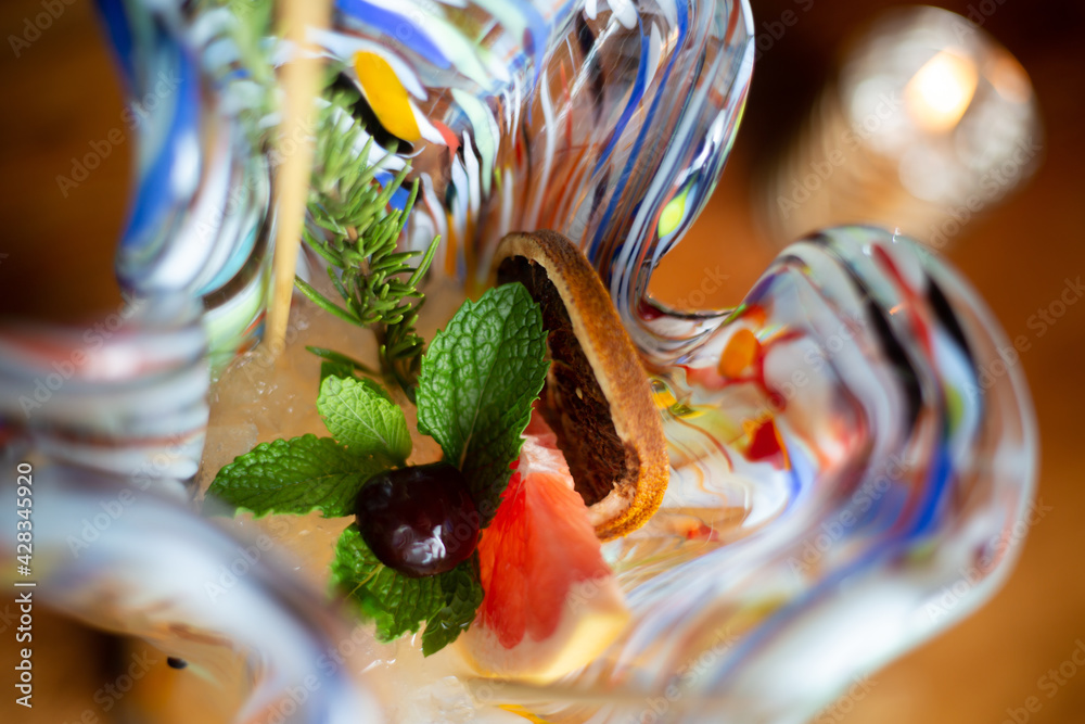 Wall mural Top view of a cocktail in colorful glass with orange and dried lemon slices, mint and fir branch