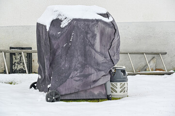 covered gas grill standing outdoors in snow
