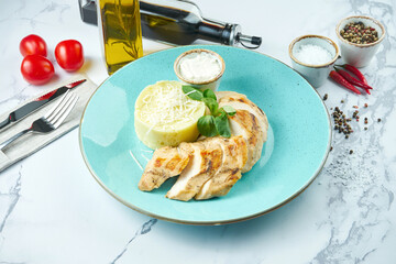 Appetizing and dietary dish - baked chicken breast with cheese sauce and mashed potatoes in a blue plate on a marble background.