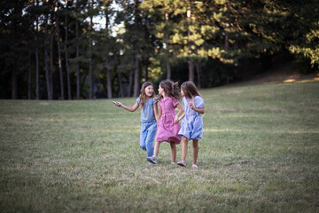 Fototapeta premium Summer day. Three little girls walking trough nature together.