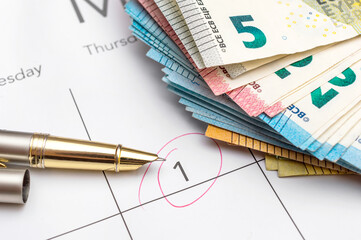 Payment day highlighted on calendar with heap of euro bills. Close up. Business concept.