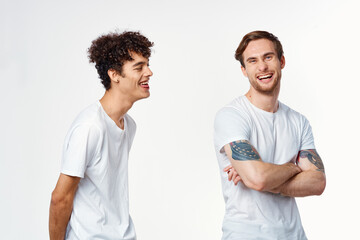 Two cheerful friends in white t-shirts stand side by side cropped view