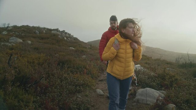 Cinematic moody and atmospheric shot of young couple on difficult treacherous hike high up in mountains on altitude. Relationship goals and wanderlust travel lifestyle. Explore nature and outdoors