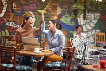 Two cheerful female students are laughing while spending a free time in bar's garden together. Leisure, bar, friendship, outdoor