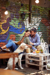 Fototapeta na wymiar A young couple in love spending a wonderful time at a bar together with their dog. Leisure, bar, friendship, outdoor