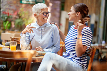 Two female friends of different generations have a friendly talk while they have a drink in the bar. Leisure, bar, friendship, outdoor