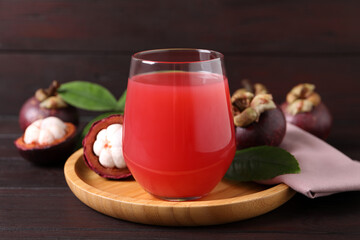 Delicious mangosteen juice in glass on wooden table