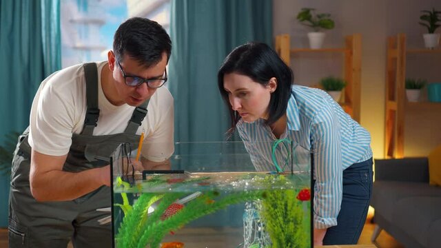 Close up service man aquarist advises a young woman about the aquarium