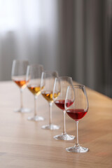 Different sorts of wine in glasses prepared for tasting on wooden table indoors