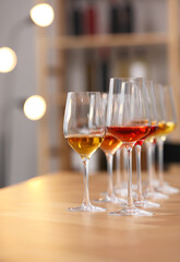 Different sorts of wine in glasses prepared for tasting on wooden table indoors