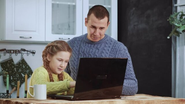 father helps schoolgirl a daughter with homework. tutor adult parent explains lessons distance homeschooling. lockdown distance learning at home concept. coronavirus. father and daughter