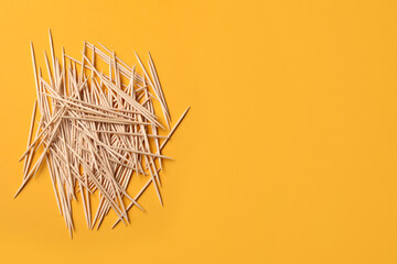 Wooden toothpicks on orange background, flat lay. Space for text