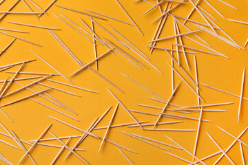 Wooden toothpicks on orange background, flat lay