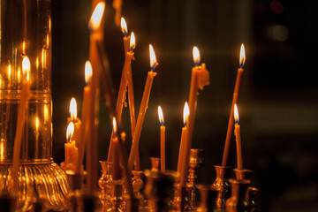 Many burning wax candles in orthodox church or temple for ceremony easter. Background orange...