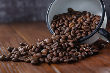 Roasted coffee beans pouring out of a white mug.Dark background