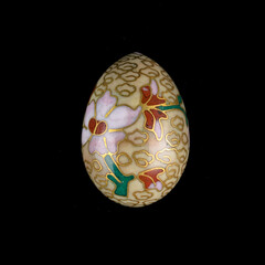 Gold wooden Easter egg with floral patterns on isolated black background