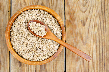 Bowl with sunflower seeds on wooden background.