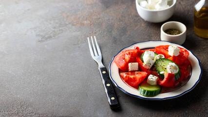 Rustic bowl with Greek salad made with fresh vegetables cucumber, tomato, sweet pepper and  feta cheese on concrete table.