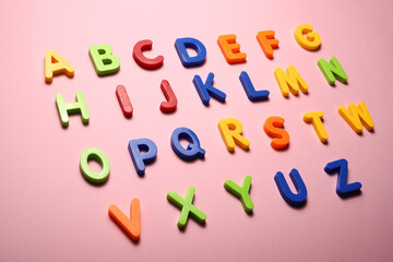 alphabet from multicolored plastic letters on a pink background