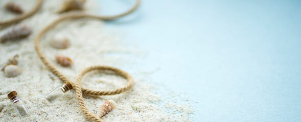 Marine composition of sand, rope, seashells and small glass bottles on a blue background. Image with selective focus