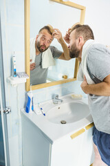Obraz premium Man using comb in bathroom