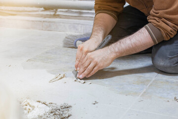 cleaning the floor manually with a construction trowel from adhering glue in the production workshop, the foreground and background are blurred with a bokeh effect