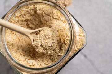 nutritional yeast in flakes, deactivated, not live, B vitamins, in a jar, focus on a spoon, close-up, top view