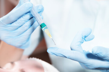 Young caucasian woman doctor dripping a drop of vaccine or injection from a syringe onto a gloved...