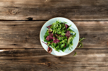 salad mix of fresh herbs, arugula, Swiss chard, spinach in tarenle on a wooden background, serhu view