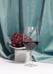 Wine glass and grapes on a concrete podium over a white background