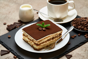 Portion of Traditional Italian Tiramisu dessert and cup of espresso coffee on grey concrete background