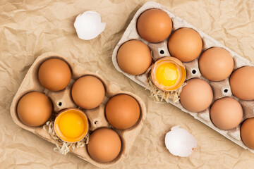 Brown chicken eggs in carton container. Broken egg in container. Eggshell on table.