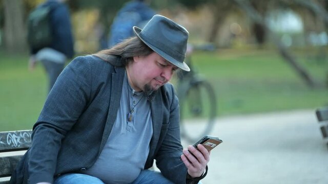 [4k] best ager on park bench reading bad news on smartphone