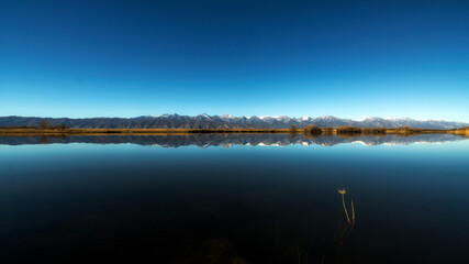 blue colour sky with reflection on water with mountains at the middle at the background like cardiogram