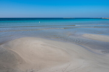 Fototapeta na wymiar Sabbia bianca con mare trasparente e cielo azzurro.