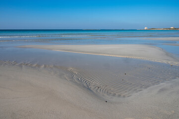 Sabbia bianca con mare trasparente e cielo azzurro.