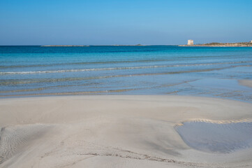 Sabbia bianca con mare trasparente e cielo azzurro.