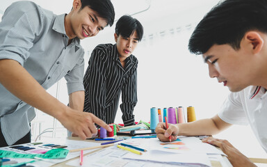 Cheerful Asian tailors working on sketches together