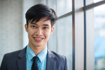 Positive Asian businessman leaning on brick wall